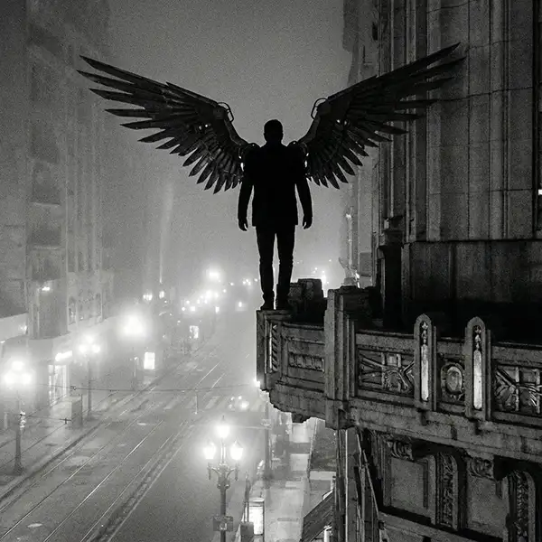 Silueta oscura de un hombre con grandes alas mecánicas o de ángel caído, parado en la cornisa de un rascacielos de estilo Art Déco. Al fondo se vislumbra una Buenos Aires nocturna y neblinosa con luces borrosas, en una estética cinematográfica noir de alto contraste.
