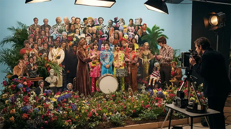 Artistas organizan una compleja escenografía llena de figuras y flores antes de una sesión fotográfica.